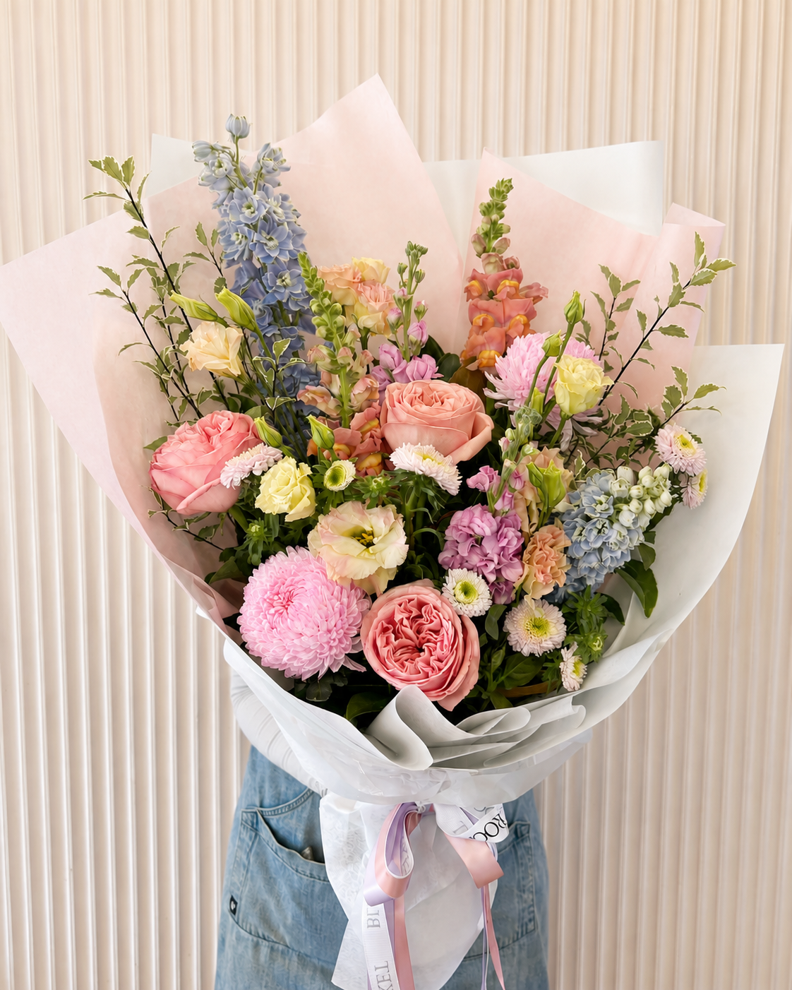 A vibrant, multicolored floral bouquet wrapped in light pink and white paper. Bloom and Rocket Florist Brisbane. Flower Delivery.