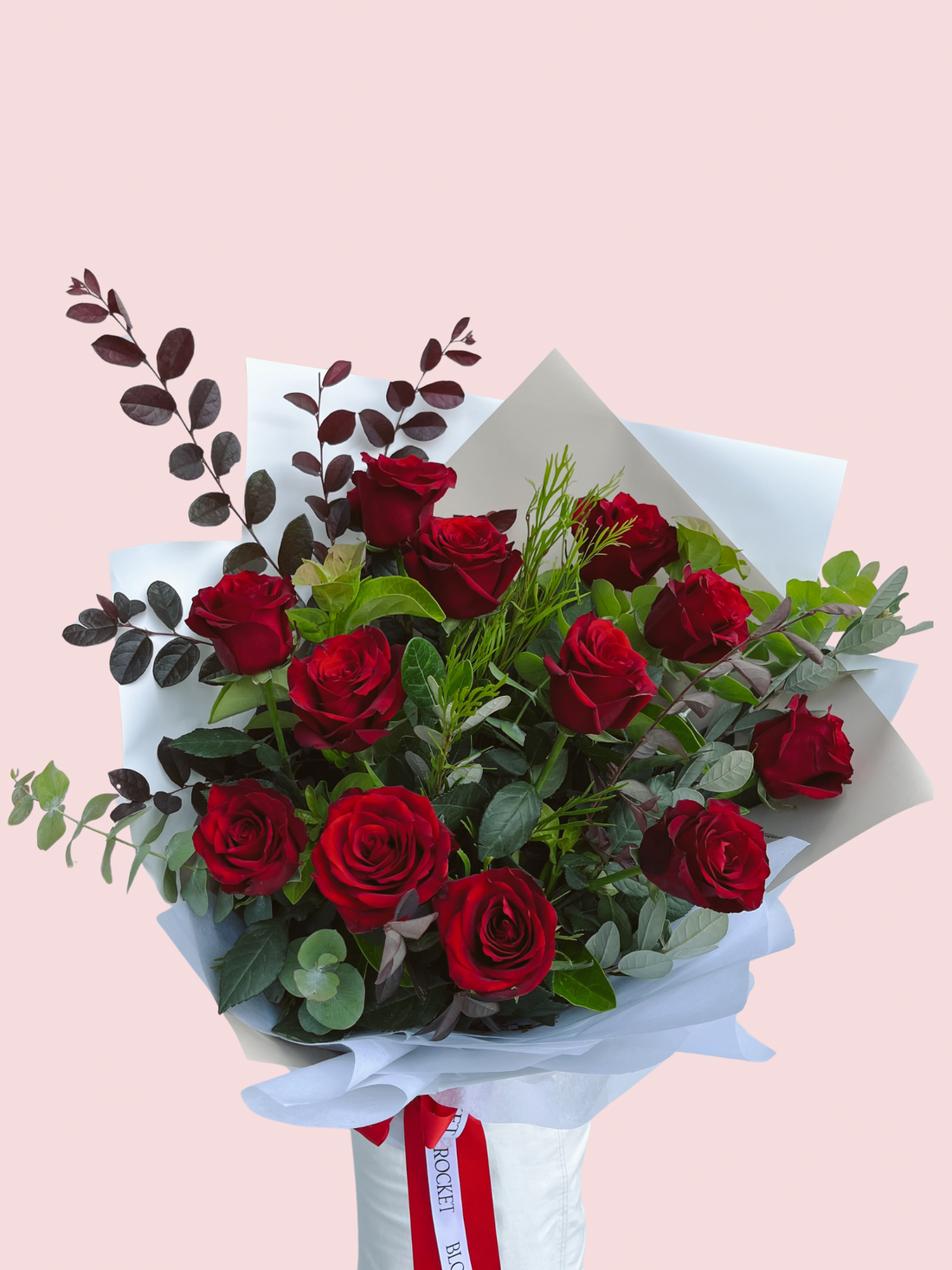 A bouquet of red long stem roses with foliage, wrapped with white paper and a red and white ribbon. Brisbane Rose delivery. Bloom and Rocket Florist.