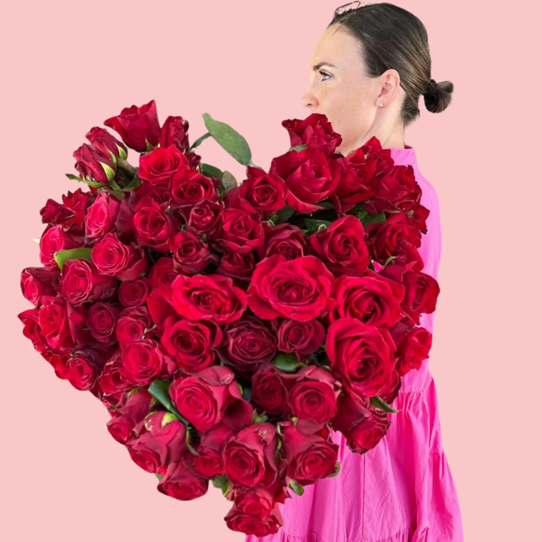 A bouquet of red long stem roses with foliage, wrapped with white paper and a red and white ribbon. Brisbane Rose delivery. Bloom and Rocket Florist, Taringa.