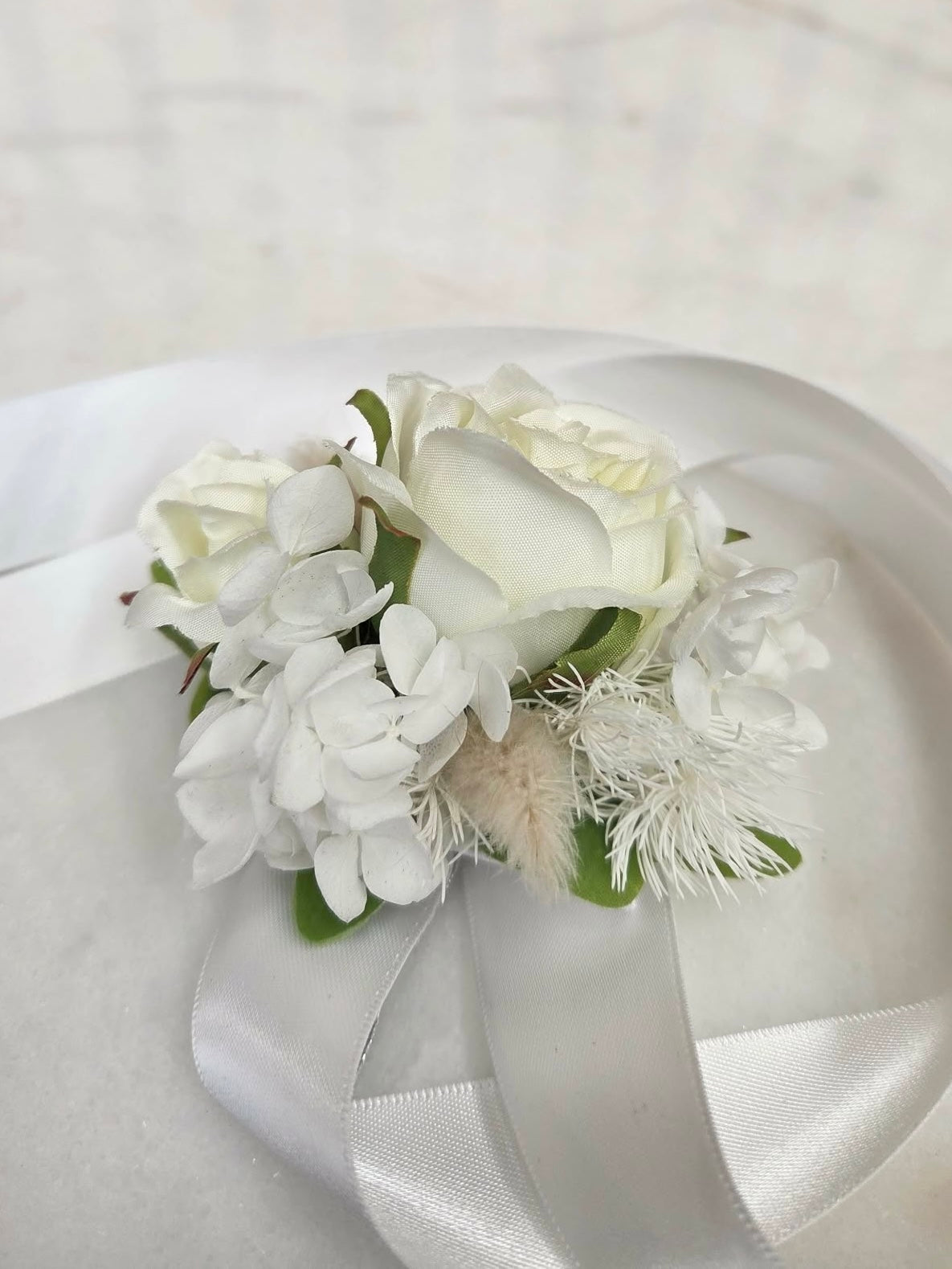 White floral corsage with ribbons on a light background