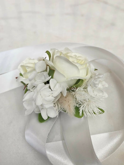 White floral corsage with ribbons on a light background
