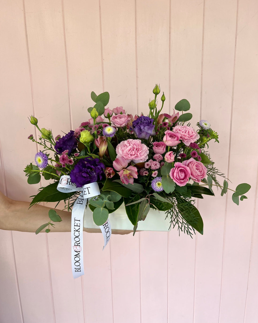 Purple and pink ceramic trough flower arrangement featuring seasonal flowers and foliage. Bloom and Rocket Florist, Brisbane.